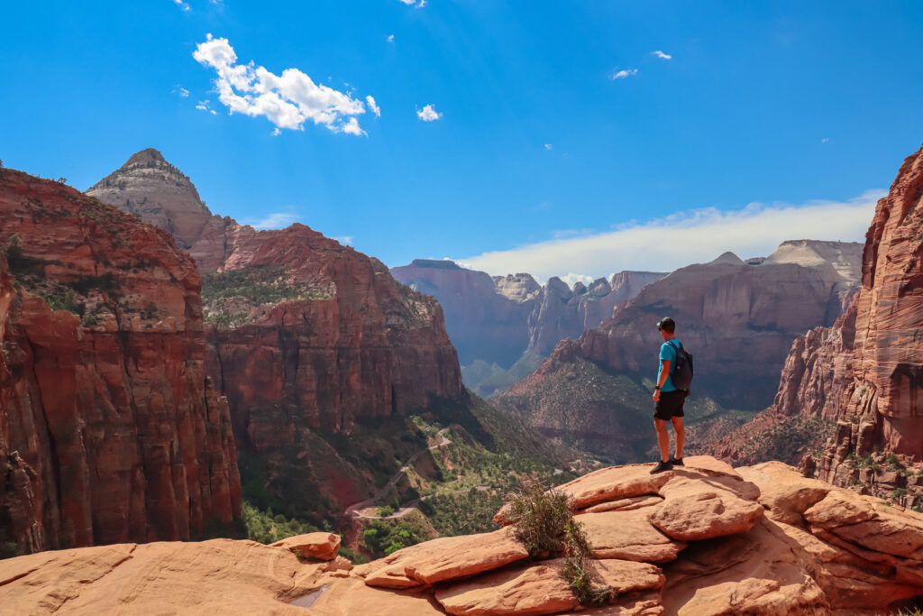 Hiker on the slickrock at Canyon Overlook looking down Pine Creek Canyon toward Zion's main canyon